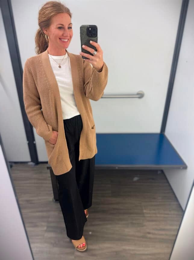 Petite woman in a long caramel cardigan and black pants