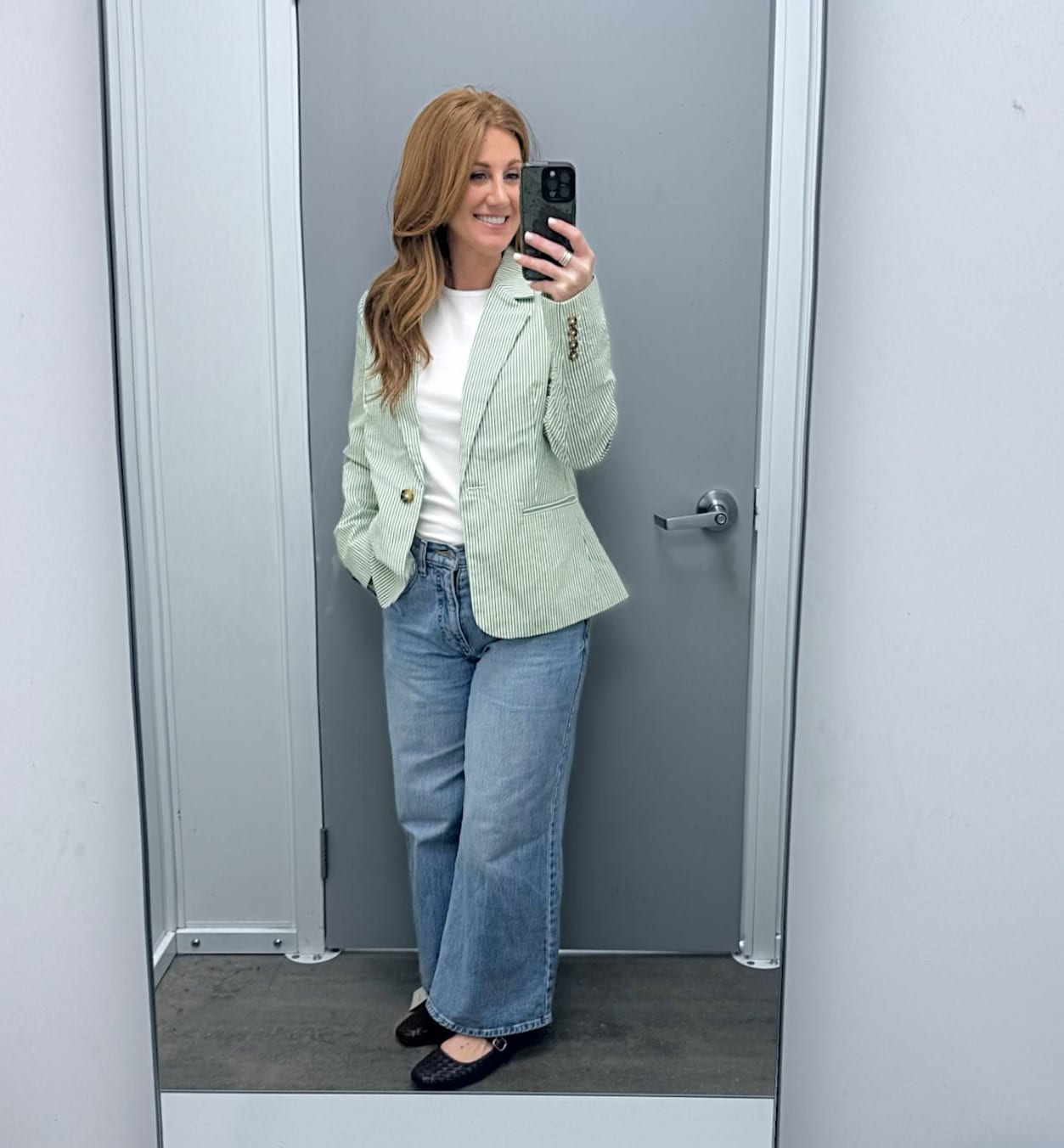Petite woman wearing a striped jacket and wide leg jeans