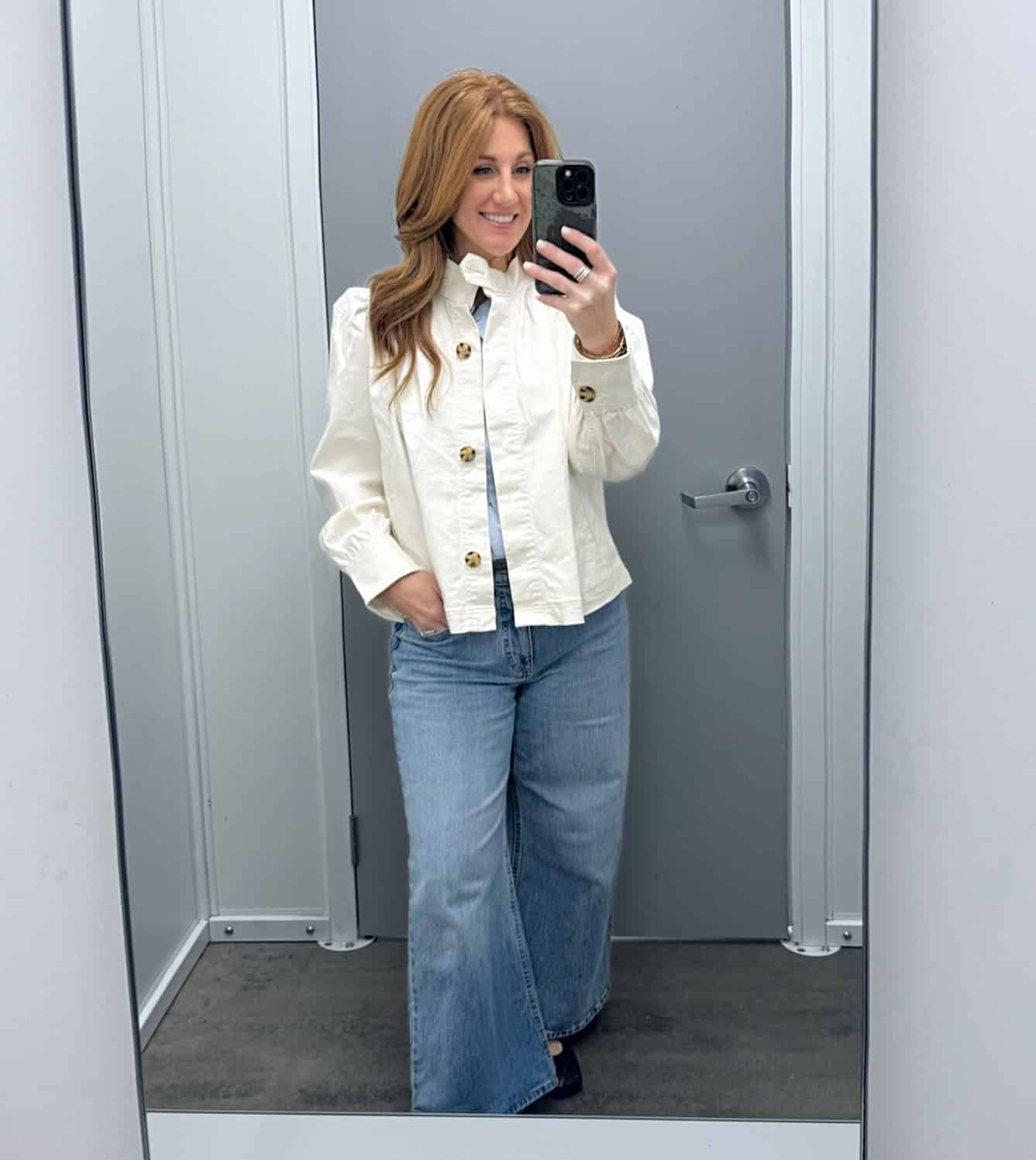 Petite woman showing a cream colored jacket with wide leg jeans