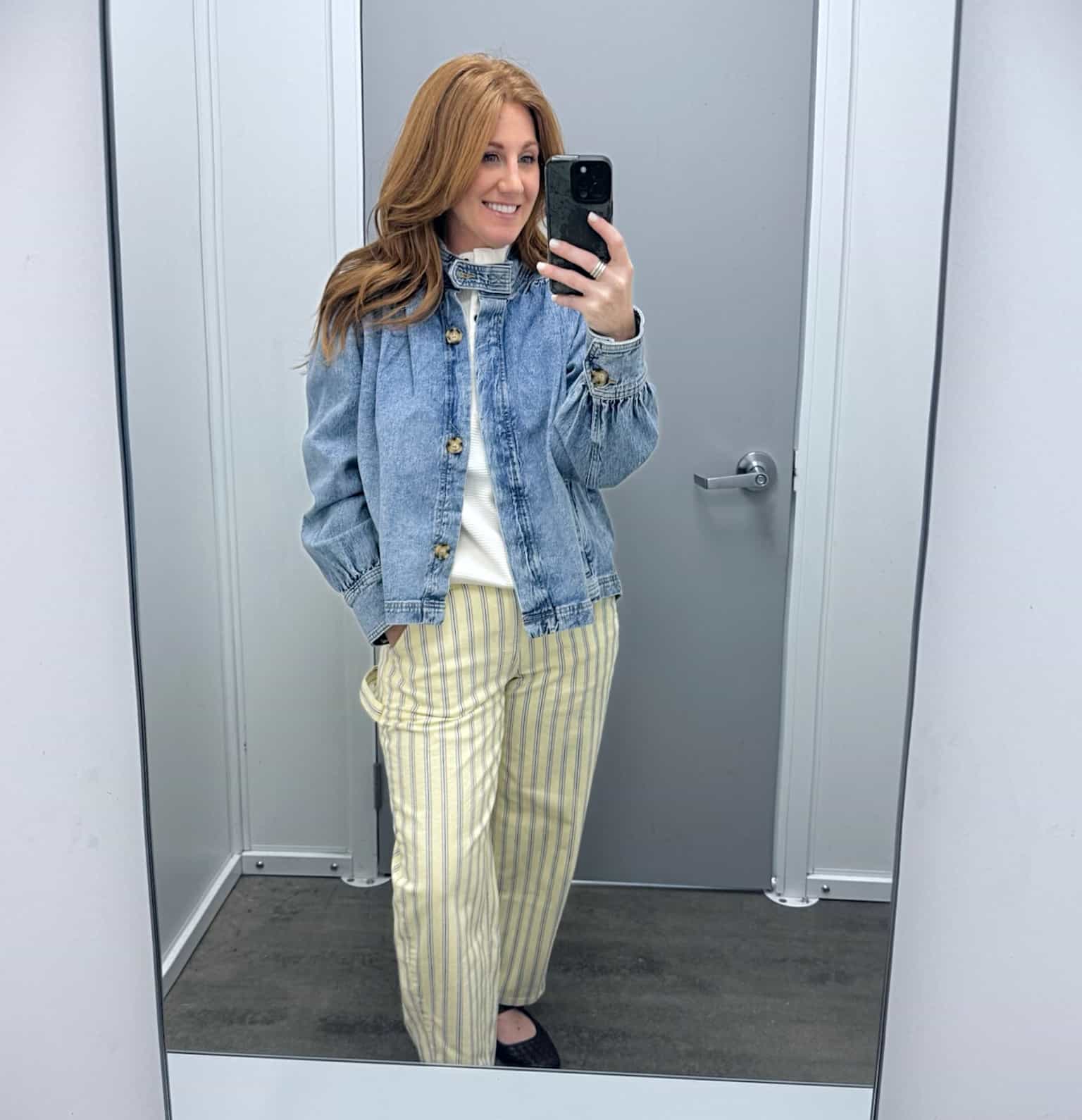 Petite woman showing a swing denim jacket with striped jeans