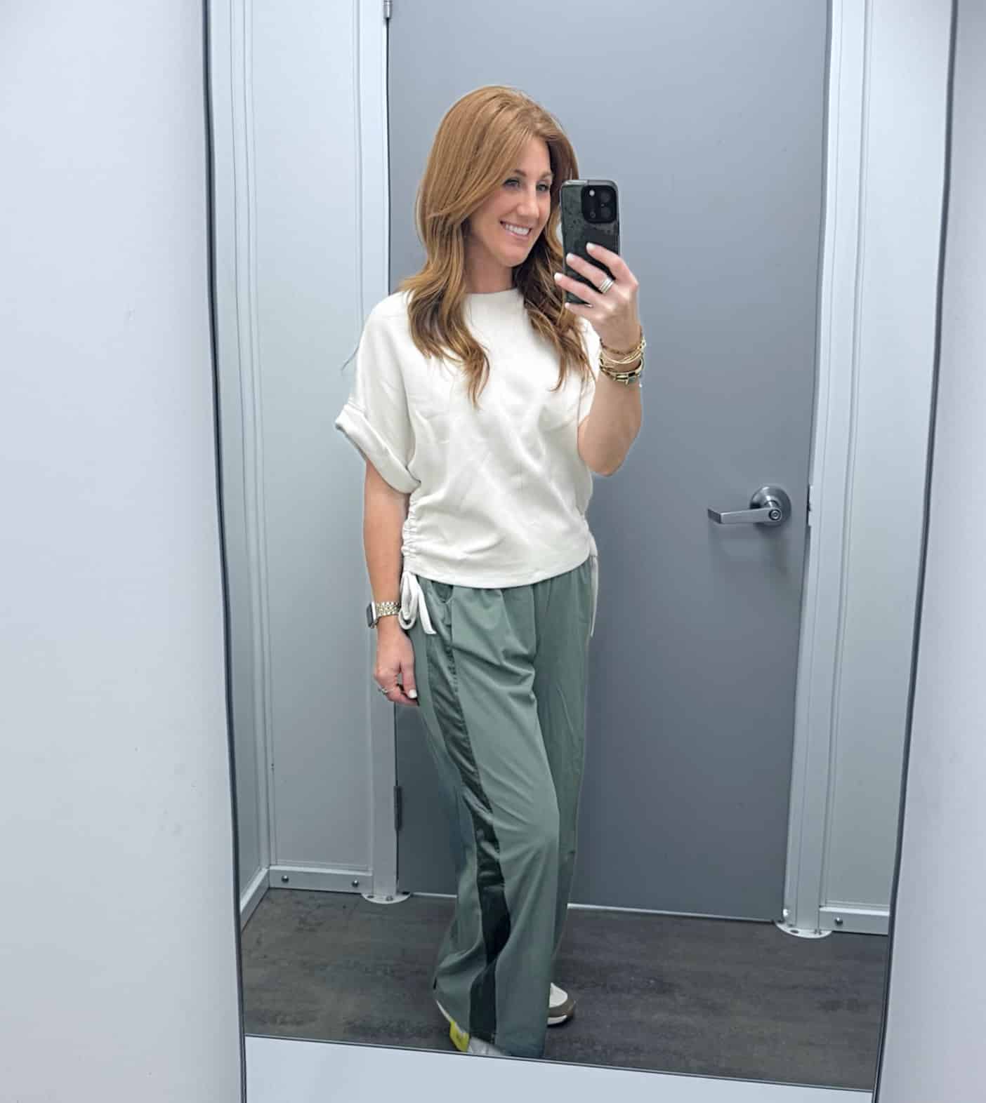 Stephanie wearing an ivory ruched top with green track pants