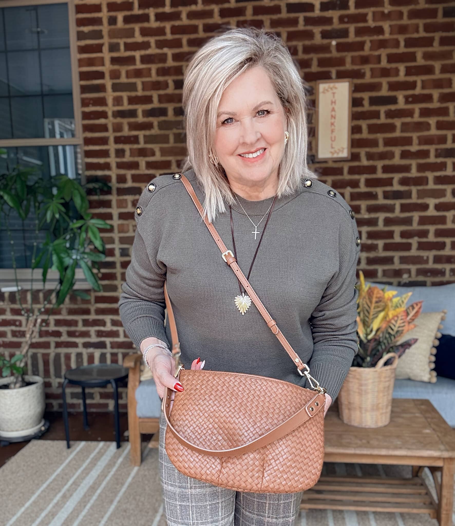 Tania wearing an olive sweater with a woven leather shoulder bag