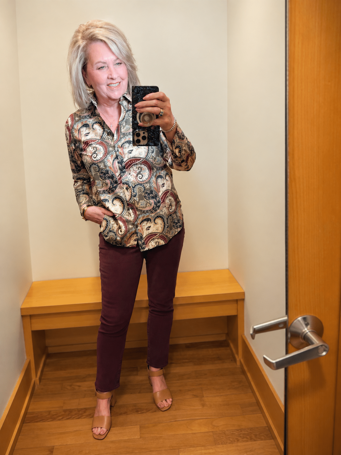Woman over 50 wearing a Chico’s paisley no-iron shirt with burgundy slim ankle jeans.