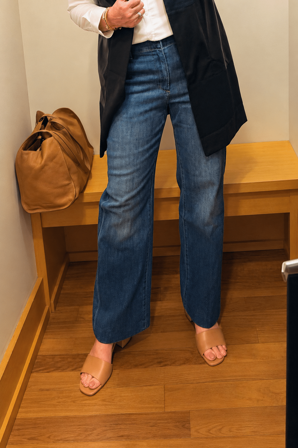 Chico’s dark-wash high-rise wide-leg trouser jeans styled with a white shirt and black vest.