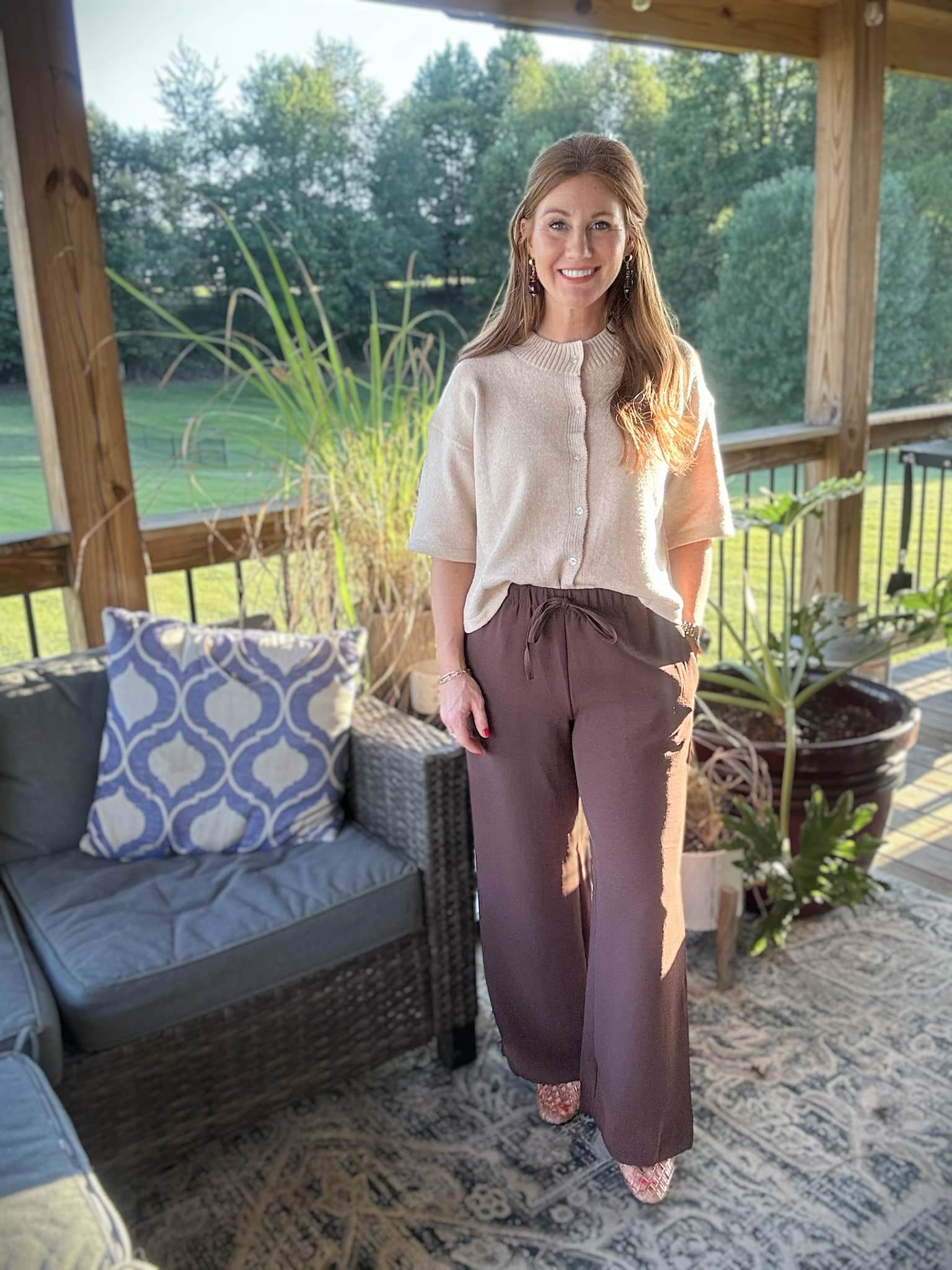 Petite woman wearing an apricot short sleeve cardigan with chocolate brown wide-leg pants