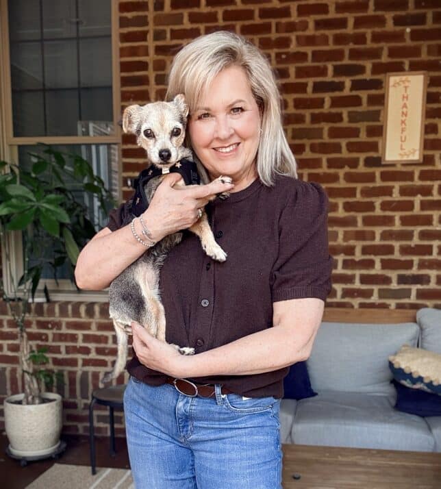 Tania wearing a dark brown sweater and holding Lucy
